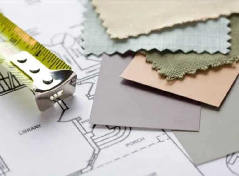 A small pile of fabric and paint samples next to a tape measure on a table
